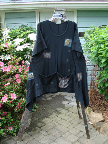 A Barclay Double Pocket Bounce Tunic Dress Cat & Mouse Black Size 2 displayed on a swinger, featuring oversized front pockets, exterior seams, and an upward scooped hemline.