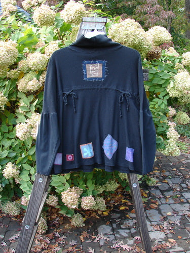 A black Pullover with patchwork designs, featuring a floppy cowl turtleneck, exterior stitchery, and painted patches. Size 3.