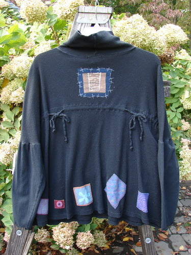 A black Pullover with patchwork designs, featuring a floppy double cowl turtleneck, exterior stitchery, and painted patches.