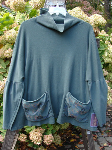 A green sweater with pockets on a swinger, featuring a floppy double cowl turtleneck, exterior stitchery, and painted patches. Size 3.