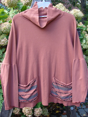 A Barclay Patched Thermal Tie Back Cowl Top in Dusty Brick, featuring a floppy double cowl turtleneck, exterior stitchery, and painted patches. With dolmen sleeves and drop pockets, this cozy top is perfect for a casual look.