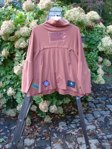 A patched rusty brick thermal Long Sleeved top with patches on a wooden stand, featuring a Barclay Patched Thermal Tie Back Cowl Top in Dusty Brick Size 3.