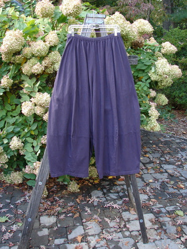 A pair of Barclay 4 Square Pants in burgundy plum, size 2, made from medium-weight organic cotton. Features a unique bottom cut that forms a 3D diamond from the knee down, with deep side pockets. Waist measures 30-40 inches, hips 84 inches, inseam 25 inches, and length 40 inches.
