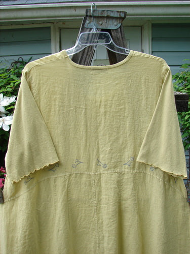 Alt text: Barclay Linen Cotton Sleeve Banded Hem Pleat Dress Falling Sprig Plantain Size 2 displayed on a hanger, showcasing its unique sectional pleats, rounded neckline, and three-quarter length sleeves.