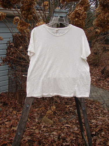 Magnolia Pearl Cotton Jersey Short Sleeved Boyfriend Tee True OSFA on a wooden ladder, showcasing its drapey feel, rolled edges, and unique wrap seam, embodying BlueFishFinder's vintage, expressive style.