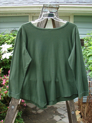Alt text: Barclay NWT Cotton Lycra Keyhole Pullover Top Unpainted Rich Clover Size 1 displayed on a clothes hanger, showcasing its long sleeves, angled flutter side hem, and keyhole center accent.