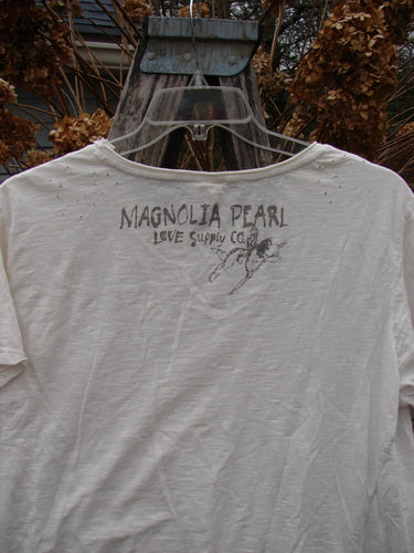 Magnolia Pearl Cotton Jersey Short Sleeved Boyfriend Tee True OSFA hangs outdoors, featuring hand-drawn MAGNOLIA PEARL Love Supply Co. text on the back, showcasing its drapey, soft cotton slub texture.