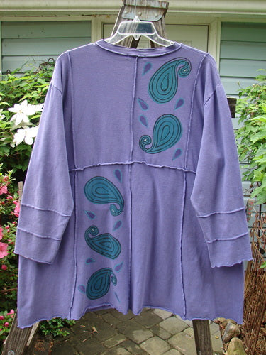 Barclay Hemp Cotton Dual Quadrant Dress Paisley Power Royal Size 2, featuring a purple paisley design, double quadrant exterior seams, varying hemline, and front drop pockets with a slight flutter.