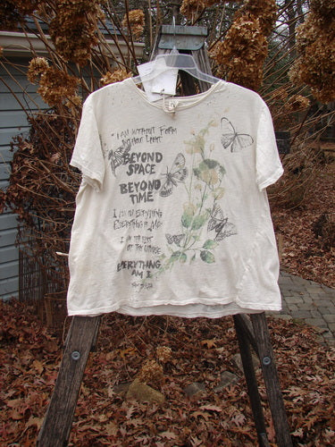 Magnolia Pearl NWT Cotton Jersey Boyfriend Tee Beyond Butterflies True OSFA showcased outdoors, featuring delicate botanical and butterfly prints with hand-lettered text, draped over a wooden frame, emphasizing its soft, drapey feel.