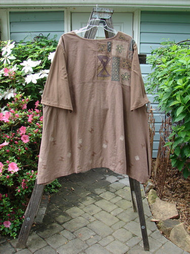 A Barclay Cotton Sleeve Hemp Linen Sectional Dress in Mandorla displayed on a clothes hanger, showcasing its contrasting three-quarter cotton sleeves and pleated A-line shape.