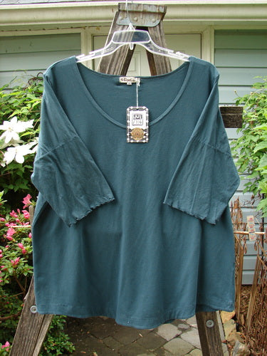 Barclay NWT Cotton Lycra Twinkle Top in Tealen Mineral, size 2, displayed on a wooden hanger, highlighting its rounded hemline, scooped neckline, and curly sleeve edges.