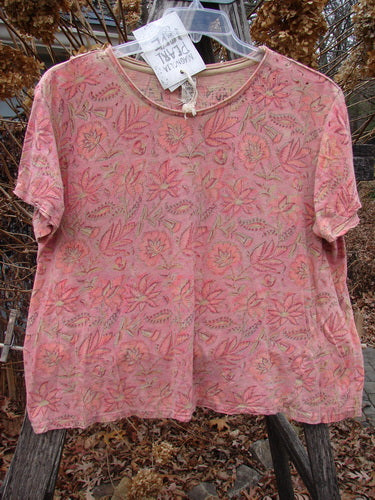 Magnolia Pearl NWT Cotton Jersey Boyfriend Tee Remi Block Print Sunset Flower OSFA, featuring a floral design, rolled edges, and shoulder distressing, displayed on a hanger outdoors against dried foliage.