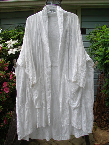 Barclay Brocade Open Front Pocket Dress Duster Unpainted White Size 2 hanging on a clothesline, showcasing its drop pockets, three-quarter length sleeves, and unique hemline.