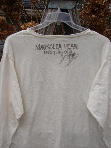 Magnolia Pearl Cotton Jersey Long Sleeved Boyfriend True OSFA, featuring Love Supply Co. print on back, hangs on a ladder, showcasing its soft drapey texture and distressed finish, embodying Bluefishfinder.com's vintage aesthetic.
