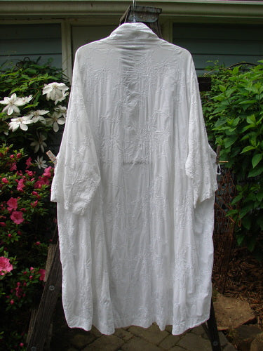 Barclay Brocade Open Front Pocket Dress Duster Unpainted White Size 2 displayed on a clothes rack, showcasing its elegant floral vine pattern, drop exterior pockets, and unique hemline.