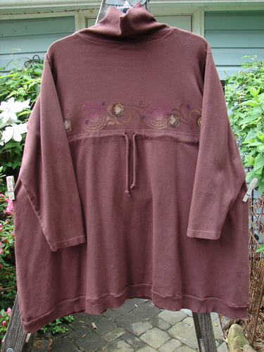 Barclay Interlock Turtleneck Pullover Tunic Top Celtic Paisley Sepia Size 2 displayed on a mannequin, featuring ribbed turtleneck, A-line shape, side pockets, banded hem, and cozy double-layered fleece fabric.