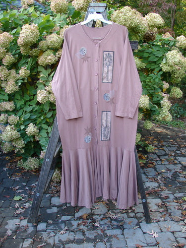 1994 Column Dress Magical Nature Cliff Size 2: A long dress on a rack, with a pink floral design. Features a full button duster shape, flounce, and V-shaped neckline.