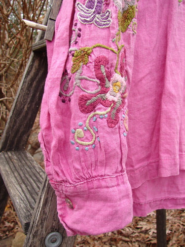 Magnolia Pearl Embroidered Linen Gypsy Johnny & Co Shirt Pinkster OSFA draped over a wooden ladder, showcasing its floral embroidery, billowy sleeves, and relaxed fit against a natural, rustic outdoor backdrop.