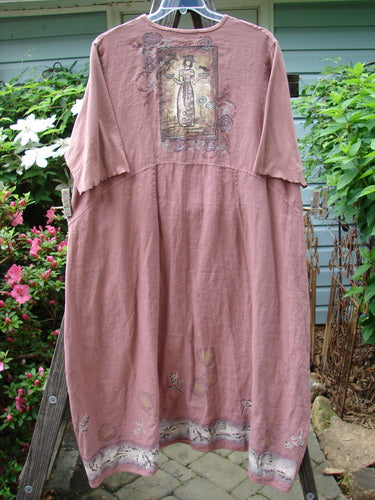 A Barclay Linen Cotton Sleeve Banded Hem Pleat Dress Bird Gal Dusty Mauve Size 2 displayed on a clothes rack, showcasing its unique pleats and three-quarter length sleeves.