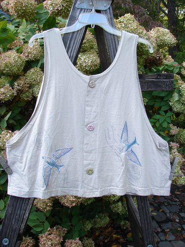 1999 Pinwheel Vest Love Dove Dust Size 2: A white shirt with birds on it. Three porcelain painted buttons, deeper arm openings, and a slightly flared hemline. Organic cotton.