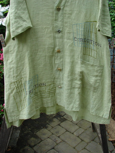 Vintage Blue Fish 2000 Cross Dye Linen Downtown Jacket in Celery, Size 2. A-line shape with ceramic glazed buttons, V-shaped neckline, and oversized pocket. Directional theme paint detail. Bust 52, Waist 56, Hips 60.