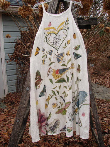 Magnolia Pearl NWT Cotton Jersey Lana Tank Dress hangs on a ladder outdoors, featuring vivid bird and botanical prints, heart graphic Peace, Pearl & Love, with raw edges and distressed details.