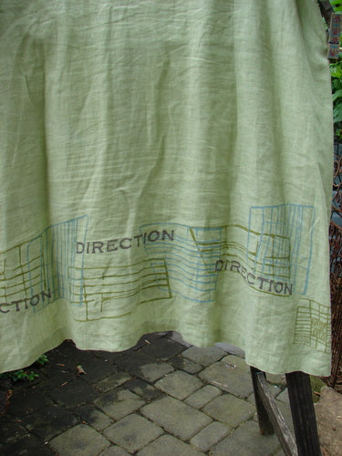 Vintage 2000 Cross Dye Linen Downtown Jacket in Celery, Size 2. A green cloth with blue and black writing, featuring ceramic glazed buttons, A-line shape, and V-shaped neckline. From BlueFishFinder.com, offering unique vintage Blue Fish Clothing by Jennifer Barclay.