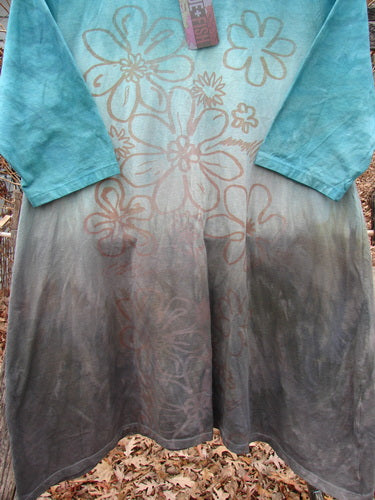 Barclay NWT Wander Tunic Tee Contour Daisy Logo Bolsena Size 0, featuring long sleeves, a teal-to-brown gradient, and hand-drawn floral patterns, hangs against a backdrop of autumn leaves.