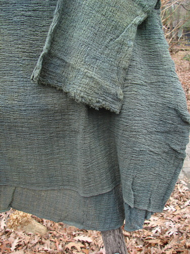 Barclay NWT Crinkle Gauze Top Mottled Evergreen OSFA displayed on a branch outdoors, highlighting its textured, featherweight design and unique high-low hemline, embodying BlueFishFinder's vintage, creative clothing ethos.