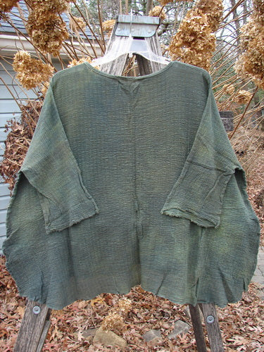 Barclay NWT Crinkle Gauze Top Mottled Evergreen OSFA: Loose-fitting green top with dolman sleeves and a high-low hem, displayed over a wooden ladder. Reflects vintage Blue Fish Clothing style in lightweight cotton.