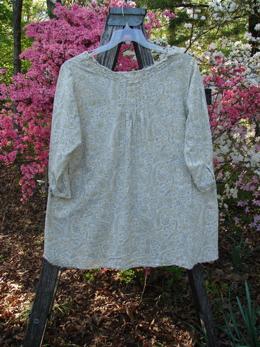 Magnolia Pearl NWT European Cotton Bondi Blouse Fleuri OSFA draped on a wooden stand, showcasing paisley print, raw-edged V-neckline, and three-quarter sleeves, set against blooming azaleas.