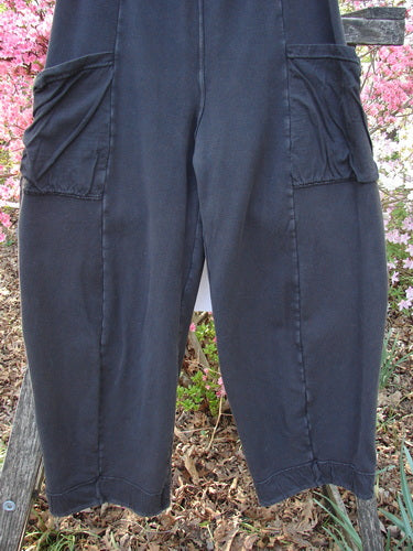 Barclay Interlock Cuff Toboggan Pant Unpainted Black Size 1 with oversized thigh pockets, exposed leg seams, and fleece cuffs, displayed outdoors against pink flowering shrubs, embodying Bluefishfinder.com's vintage, creative style.
