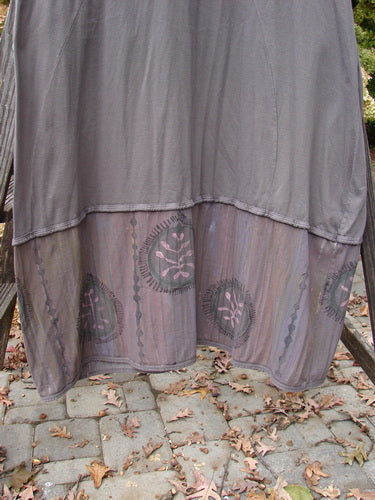 Barclay Pleated Banded Bottom Sweep Dress Celtic Fern Mushroom Size 1: A unique grey dress on a wooden stand, featuring a pleated front neckline, painted lover sleeves, and a sweeping A-line shape. It has double exterior drop pockets, a generous banded bottom sectional panel, and a downward curved empire waist seam. The dress is painted with detailed fern graphics, made from mid-weight organic cotton. Perfect condition. Length: 53 inches.
