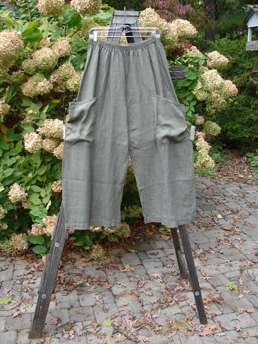 Barclay Linen Side Pocket Summer Pant on wooden stand. Size 1. Unpainted Green Stone. Medium Weight Linen. Full elastic waistline. Two front wrap exterior pockets. Slight crop length. Inseam 24. Length 38.