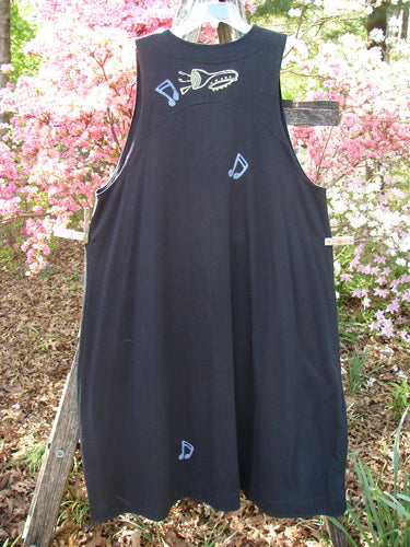1996 State Fair Vest Music Festival Storm Size 1: A sleeveless, apron-style black dress adorned with playful blue and yellow appliqué shapes, featuring a unique oversized button and double-paneled hemline, epitomizing vintage charm.