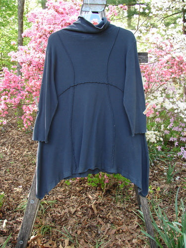Barclay Thermal Reverse Stitch Pocket Dress Unpainted Raven Size 1 displayed on a wooden ladder outdoors, surrounded by pink and white azaleas, highlighting its cozy turtleneck and oversized front pockets.