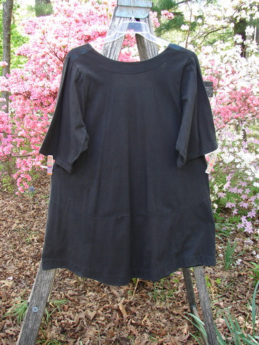 Barclay Short Sleeved Be There Top Floral Bud Black Size 1 displayed on a wooden ladder. Features include a square neckline, empire waist seam, lower banded hem, and angular pockets, set outdoors.