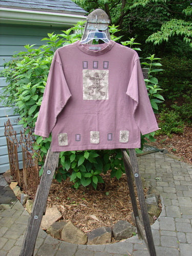 1996 Long Sleeved Tee Frog Pond Petunia Size 0 displayed on a wooden ladder, featuring a graphic frog theme, thicker ribbed neckline, and Blue Fish patch, made from mid-weight organic cotton.