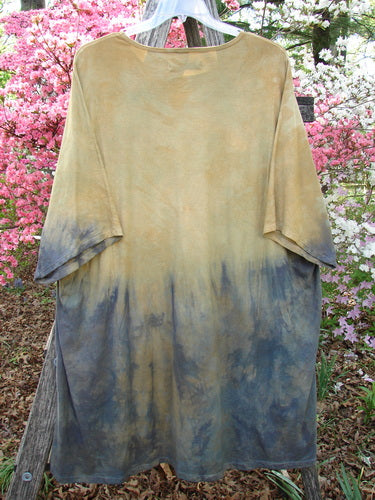Barclay Art Tunic Tee Mottled Sun Field and Night OSFA hanging outdoors, showcasing its dip-dyed design with loose three-quarter sleeves, rounded neckline, and varying hemline against a floral backdrop.