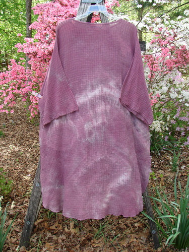 Barclay Crinkle Gauze Ana Tunic Dress Unpainted Mottled Rusty Rose OSFA, displayed on a wooden ladder with three-quarter sleeves and a varying hemline, set against a garden backdrop with pink azaleas.