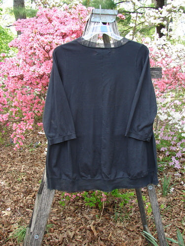 Barclay Flutter Edged Essential Tee Lightning Black Size 1 hangs gracefully on a ladder, showcasing its three-quarter length sleeves with raw edges and a slightly flared mesh hemline.