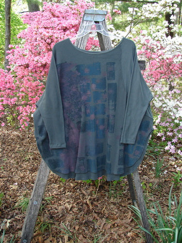 Barclay Thermal Monte Verde Vented Tunic Night Black Army OSFA displayed on a ladder in a garden, showcasing its loose fit, rounded neckline, side vents, and exterior stitchery.