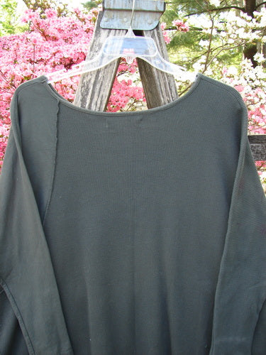 Barclay Thermal Monte Verde Vented Tunic Night Black Army OSFA hanging on a wooden fence, showcasing its rounded neckline, ribbed sleeves, and unique stitchery, embodying Bluefishfinder.com's vintage, expressive style.