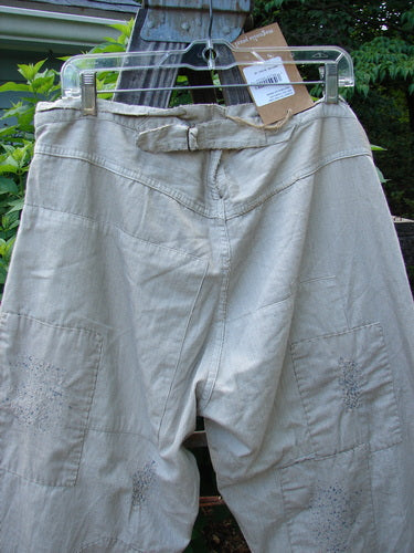 Magnolia Pearl NWT Patched Lilou Trouser on a clothesline, showcasing European Cotton Stripe Linen. Features include Button Front Fly, Overlay Patches, and Distressed Details. Reflects BlueFishFinder's unique vintage clothing ethos.