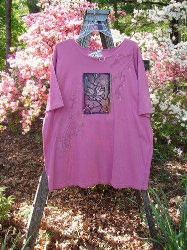 Barclay NWT Short Sleeved Studio Tee Single Cherry Blossom Alegra Size 3, displayed on a wooden ladder in a garden, features a stylized flower motif and vine accents, set against blooming shrubs.