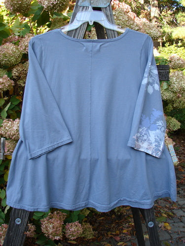 A Barclay Three Quarter Sleeved Crop A Lined Top in Sky Grey, featuring a blue shirt on a clothes rack. Graduating A Line Shape, Rounded and Rolled Neckline, Sweet Curly Edgings, Unadorned Back, and Lovely Detailed Elements Theme Paint. Bust 48, Waist 50, Hips 54, Sweep 70, Length 28 Inches.