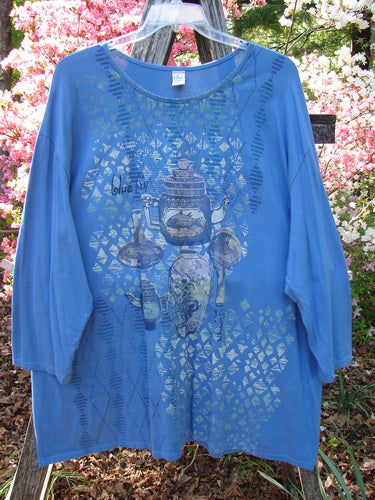 Barclay Long Sleeved Studio Tee Blue Fish Logo Ginger Jar Skylark Size 3: A loose-fitting, three-quarter sleeve top in cornflower blue, featuring a still-life motif over a geometric mosaic pattern.