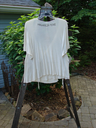 Magnolia Pearl NWT Ribbed Origami Wrap Blouse Moonlight OSFA hanging on a clothesline, showcasing its deep neckline, two-tie exterior, three-quarter wide sleeves, and varying hemline.
