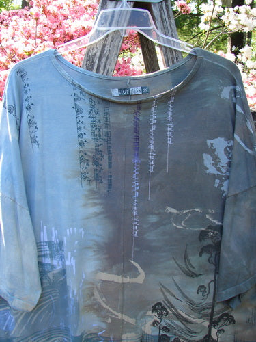 Barclay Center Seam Wide Line Tee Windy Bonsai Mottled Day Storm OSFA drapes over a wooden rail, showcasing its abstract brush-stroke and Asian-style script prints, with a unique boxy shape and drop shoulders.