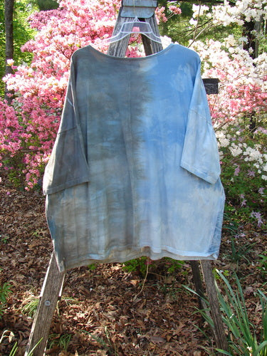 Barclay Center Seam Wide Line Tee Windy Bonsai Mottled Day Storm OSFA hanging on a ladder clothesline, featuring a rounded neckline and drop shoulders, set against blooming azalea bushes in a garden.